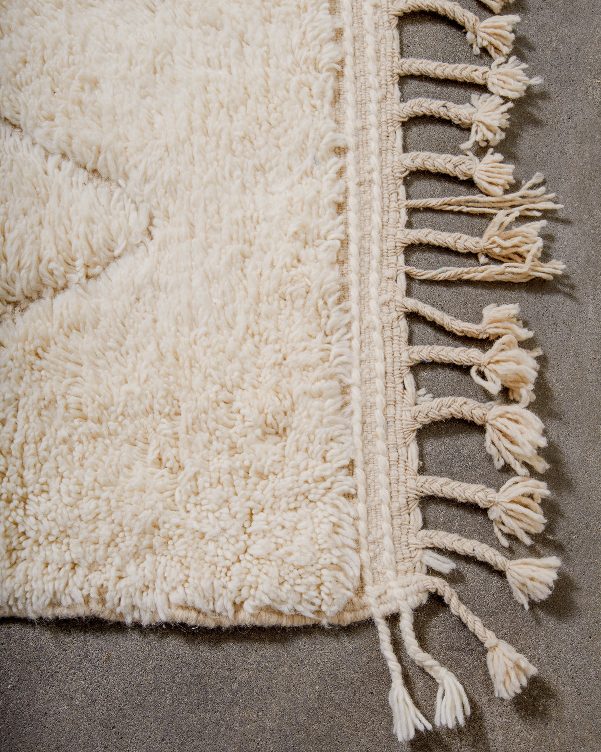 Corner of beniourain rug with tightly woven end and natural wool tassels.